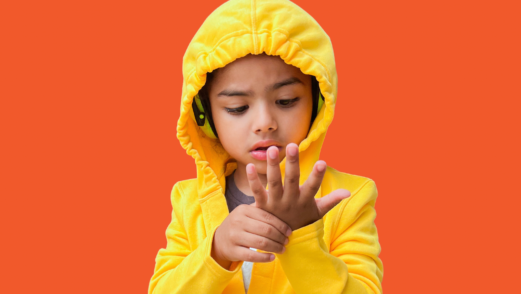 Autistic child in a sensory friendly hoodie and sensory friendly pants. He is wearing noise cancelling headphones under his sensory friendly hood.