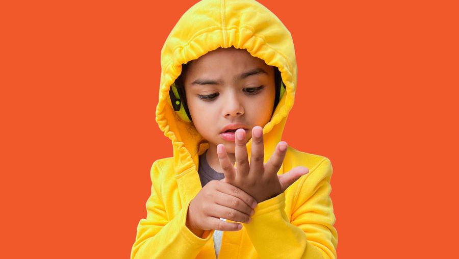 Autistic child in a sensory friendly hoodie and sensory friendly pants. He is wearing noise cancelling headphones under his sensory friendly hood.