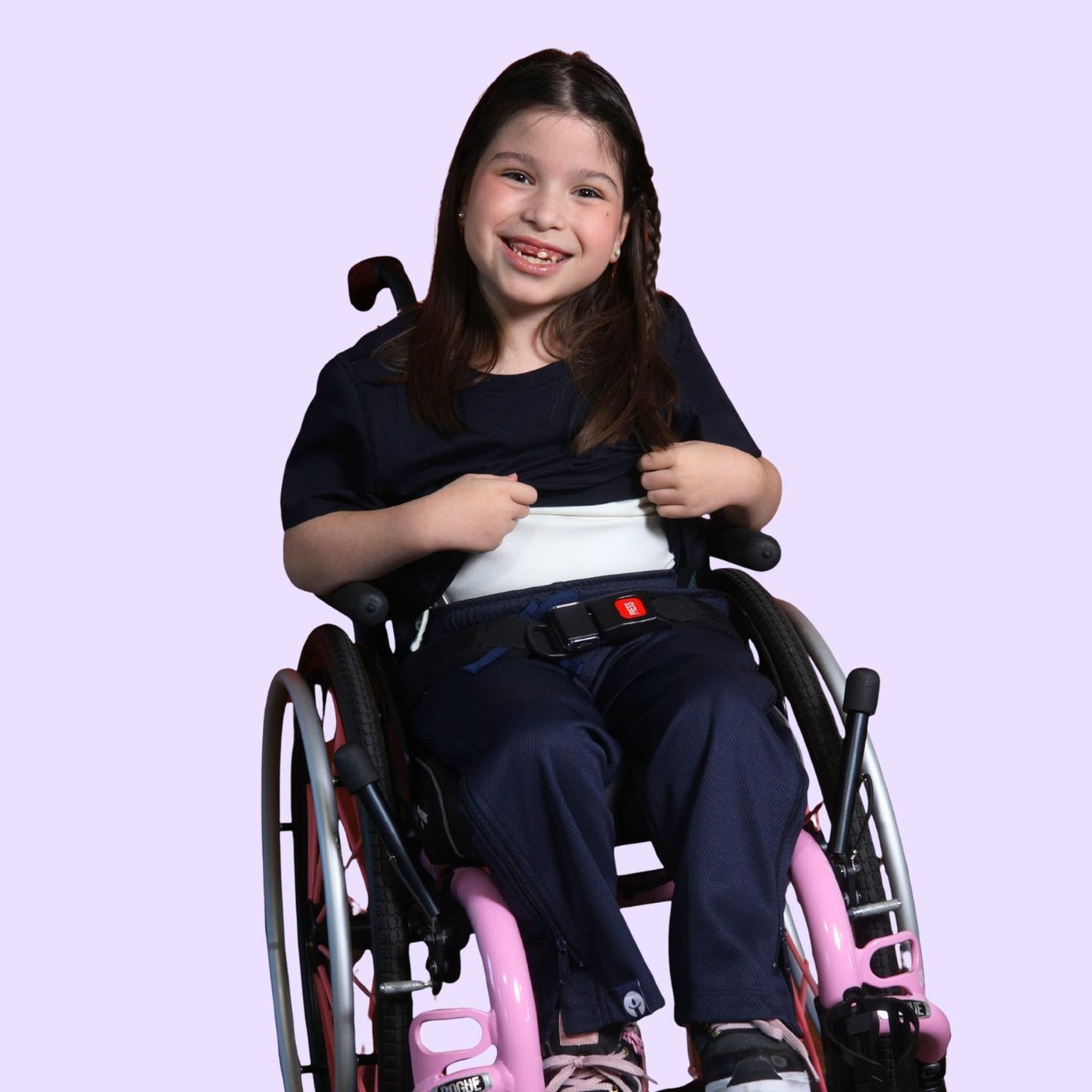 Young girl in a wheelchair holding up her sensory t-shirt to show the compression lining.