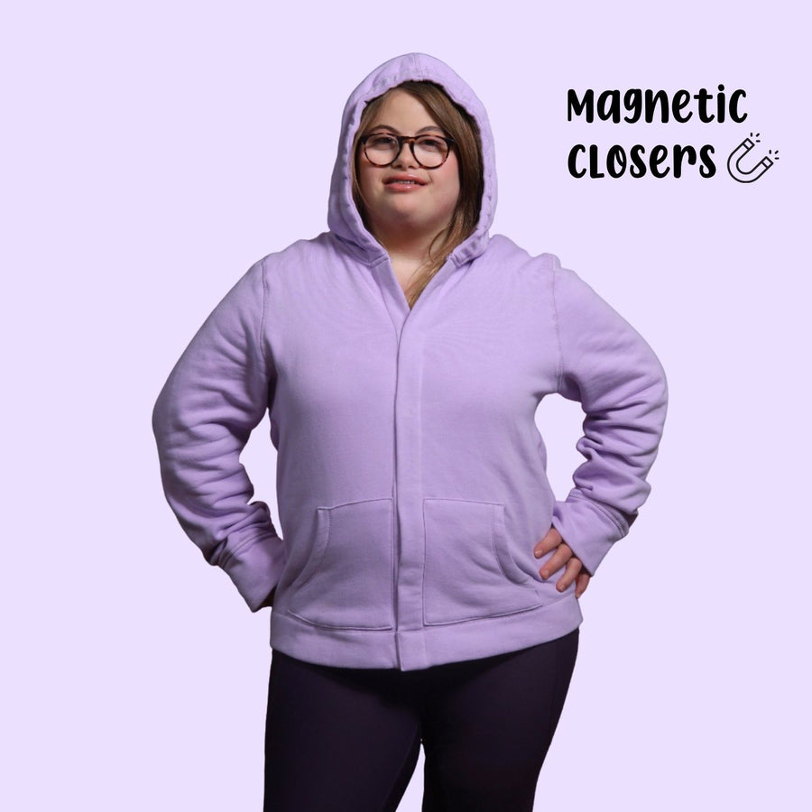 Adult with down syndrome wearing sensory hoodie with sound reducing hood pulled up and magnetic closures shut. 