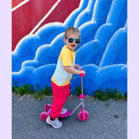 Child on a scooter in front of a colorful wall with blue and red design