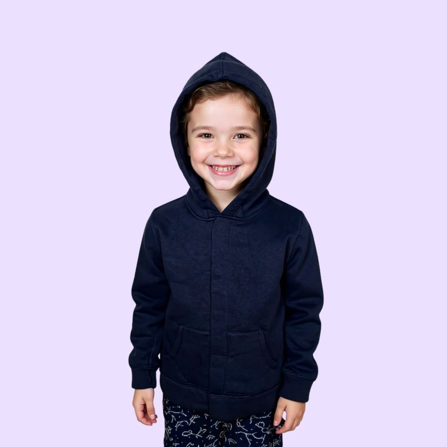 Autistic child wearing navy sound reducing sensory hoodie with adaptive magnetic closure.