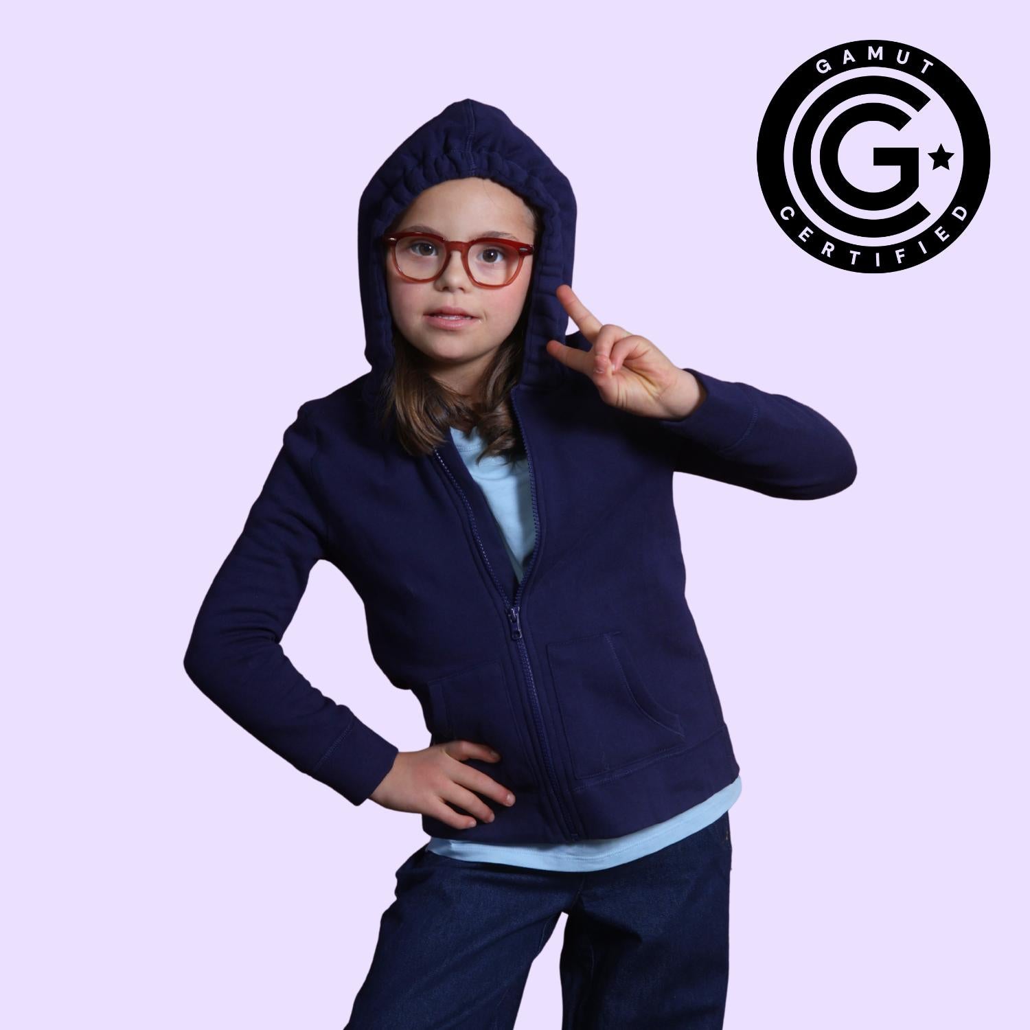 Girl with down syndrome holding up a peace sign while wearing the sound reducing hood up on her sensory break hoodie with GAMUT Seal of Approval™ in the top right corner.