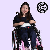 Young girl in a wheelchair holding up her sensory t-shirt to show the compression lining. GAMUT Seal of Approval™ in the top right corner.