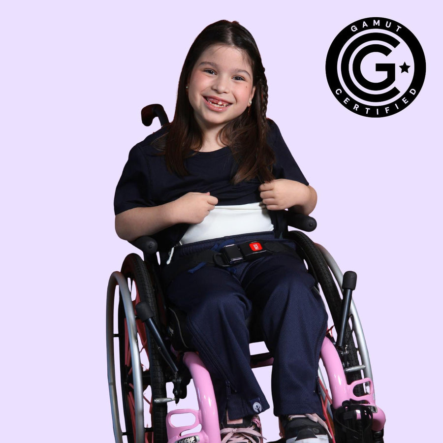 Young girl in a wheelchair holding up her sensory t-shirt to show the compression lining. GAMUT Seal of Approval™ in the top right corner.