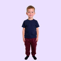 Child wearing a navy compression shirt and red pants on a light purple background