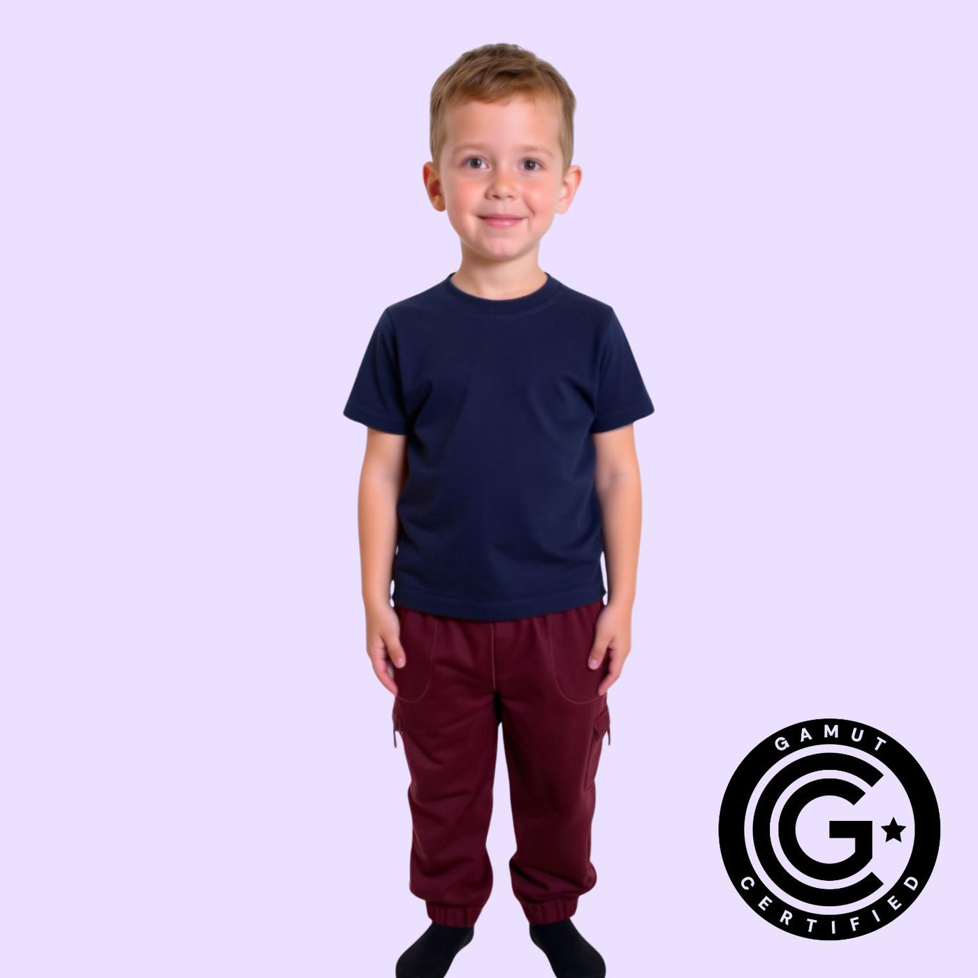 Child wearing a navy compression shirt and red pants on a light purple background. GAMUT Seal of Approval™ in bottom right corner.