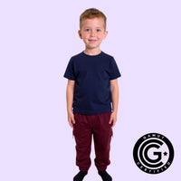 Child wearing a navy compression shirt and red pants on a light purple background. GAMUT Seal of Approval™ in bottom right corner.