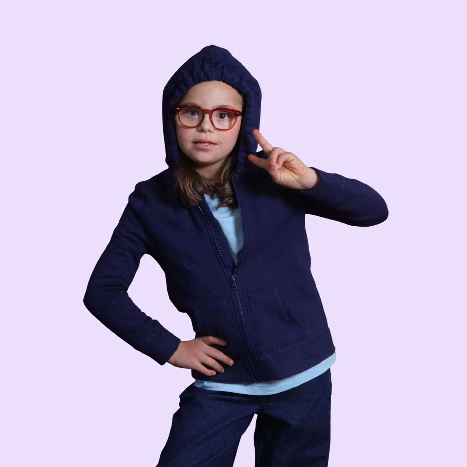 Girl with down syndrome holding up a peace sign while wearing the sound reducing hood up on her sensory break hoodie